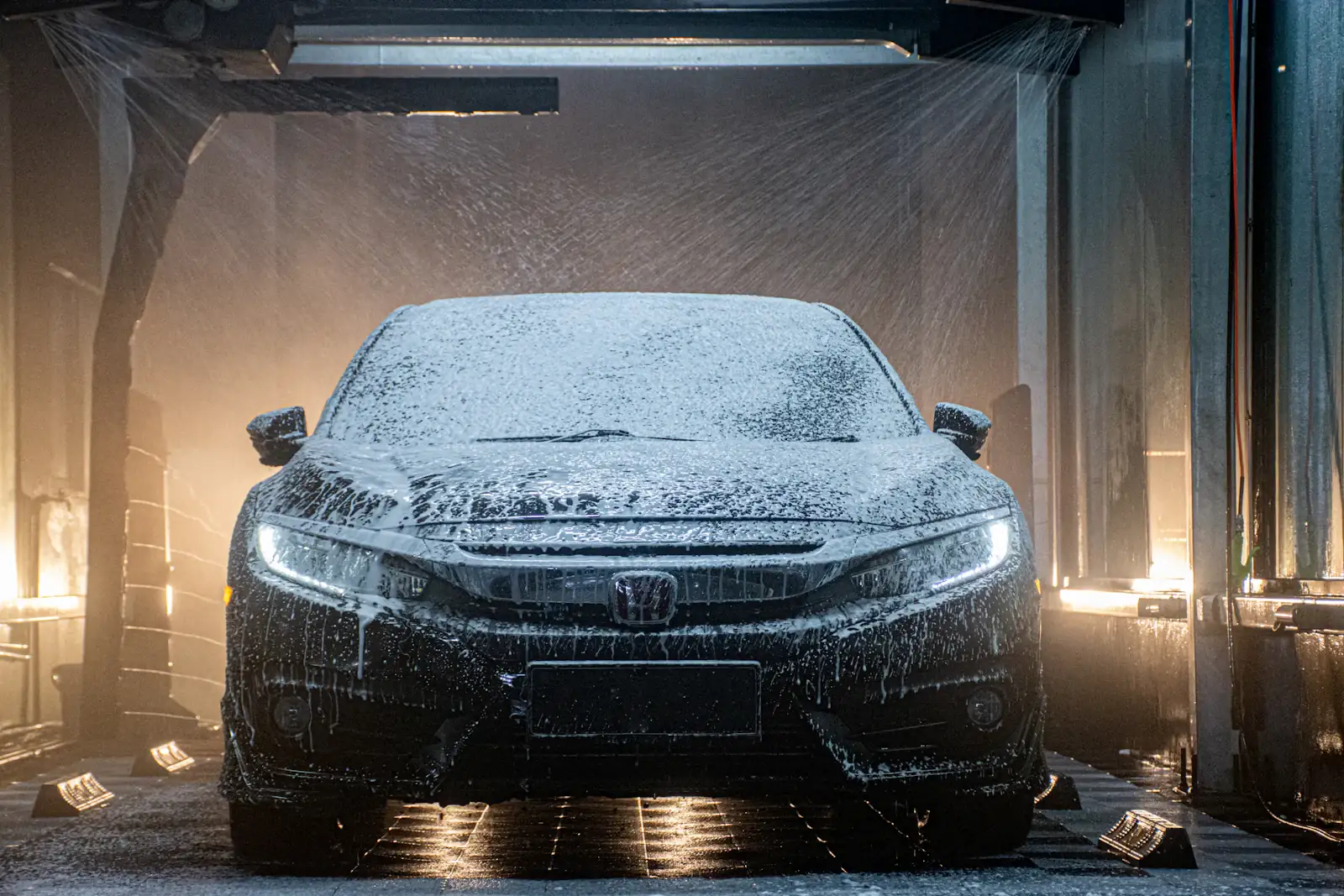 Voiture couverte de mousse dans un atelier sombre, phares allumés